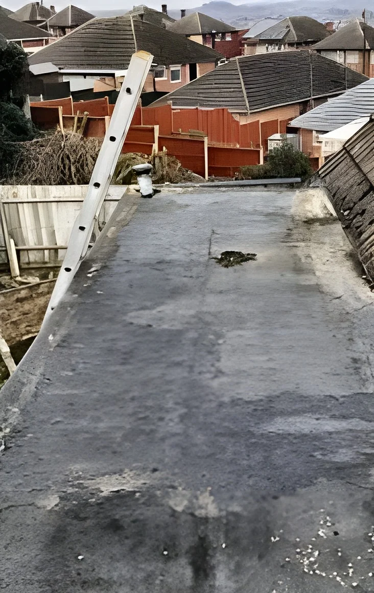 Old flat garage roof with a worn, patched and ponding felt covering